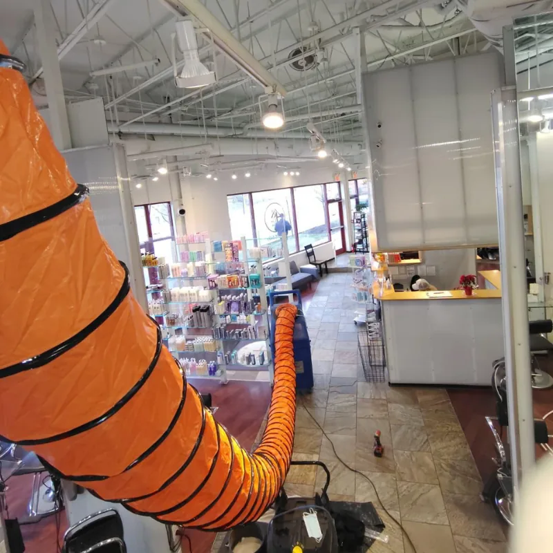 Commercial air duct cleaning in a retail store using an orange HEPA vacuum duct