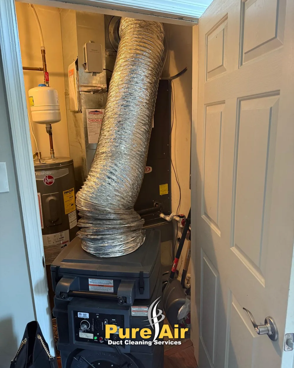 HEPA air duct cleaning machine connected to a home's HVAC system in a utility closet