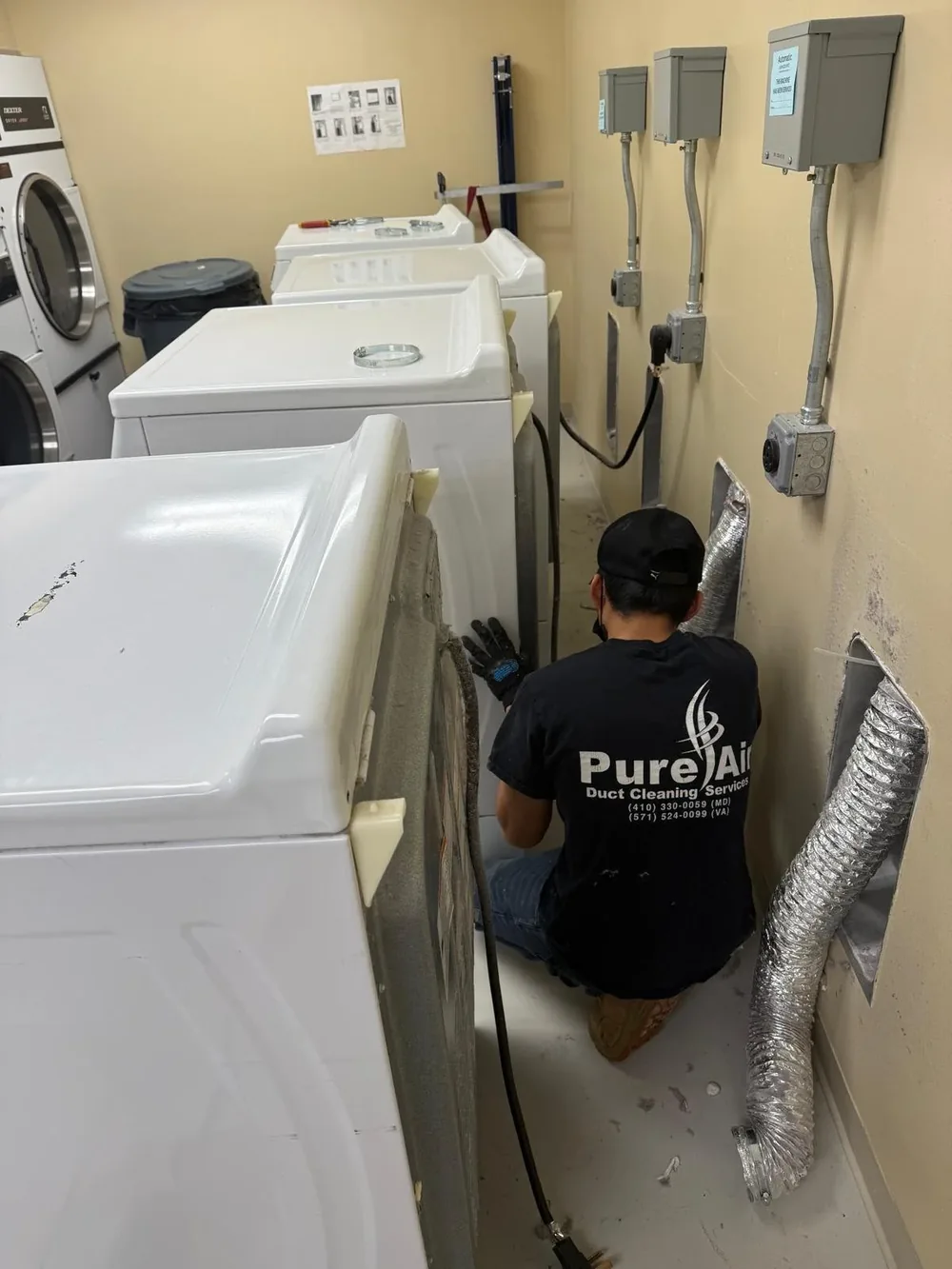 Pure Air technician cleaning dryer vents in a multi-unit laundry room
